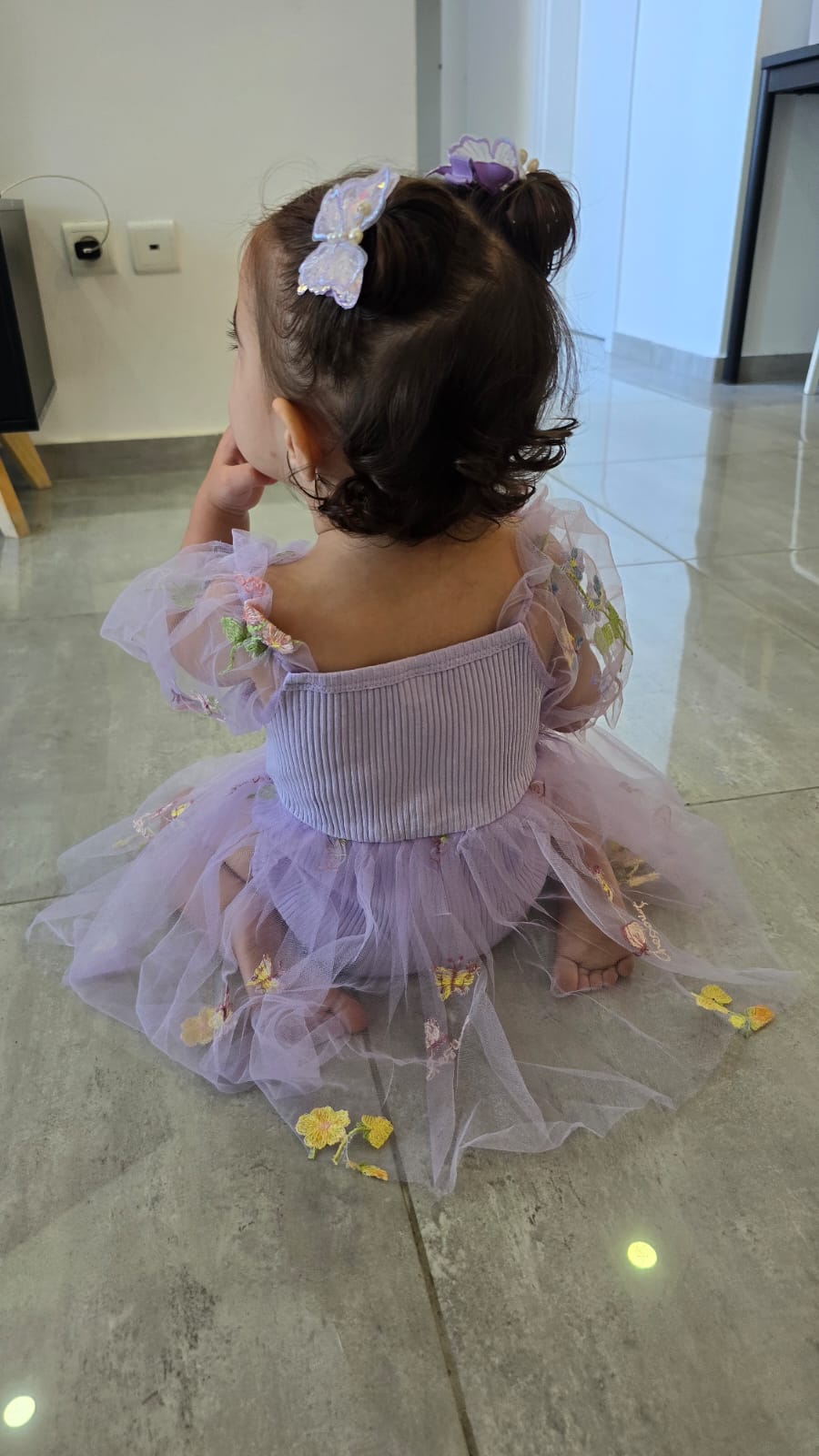 שמלה לתינוקות מעוטרת רקמות פרפרים ופרחים צבעוניים.