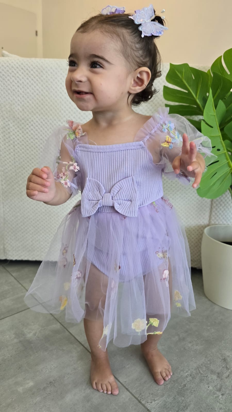 שמלה לתינוקות מעוטרת רקמות פרפרים ופרחים צבעוניים.